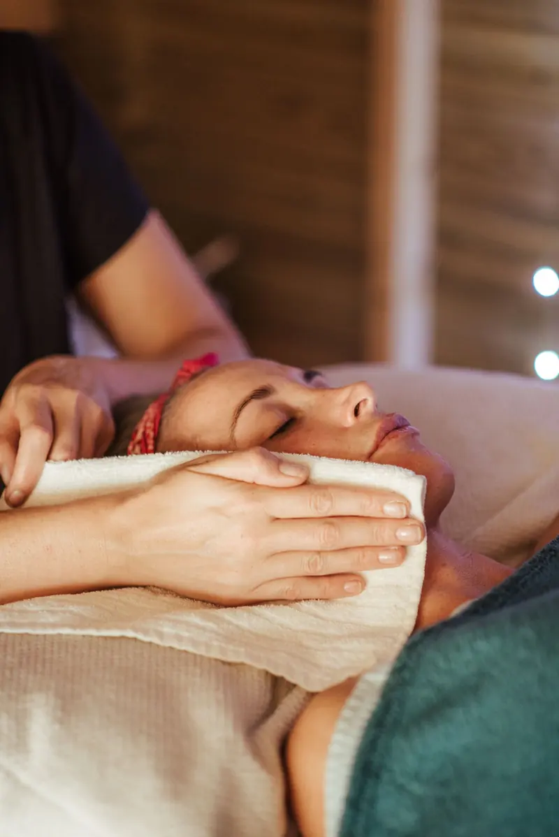 Mujer relajada durante un masaje facial en una cabina de estética