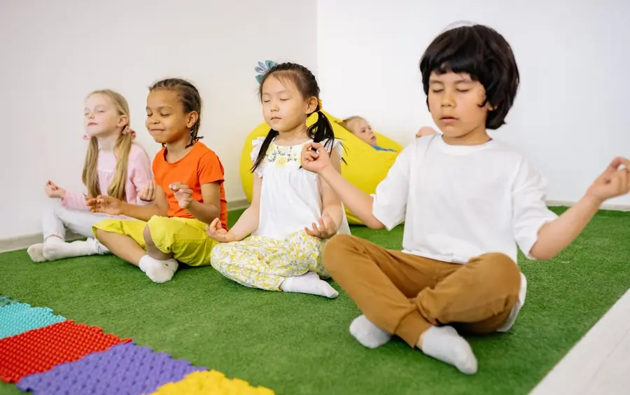 Niños sentados con las piernas cruzadas respirando con los ojos cerrados